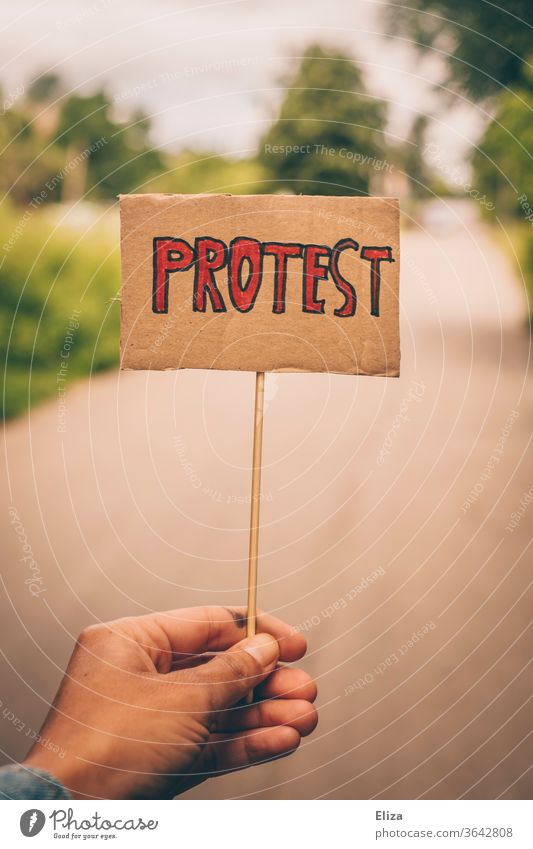 One hand holds a sign with the word protest. Concept demonstration, resistance. Demonstration on the other hand rejecting Protest demonstrate by hand anti