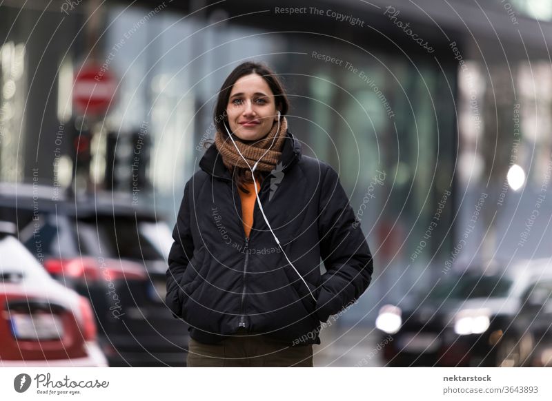 Young Indian Woman with Sincere Smile on Street young woman Indian ethnicity music earphones medium shot audiobook listening focus on foreground