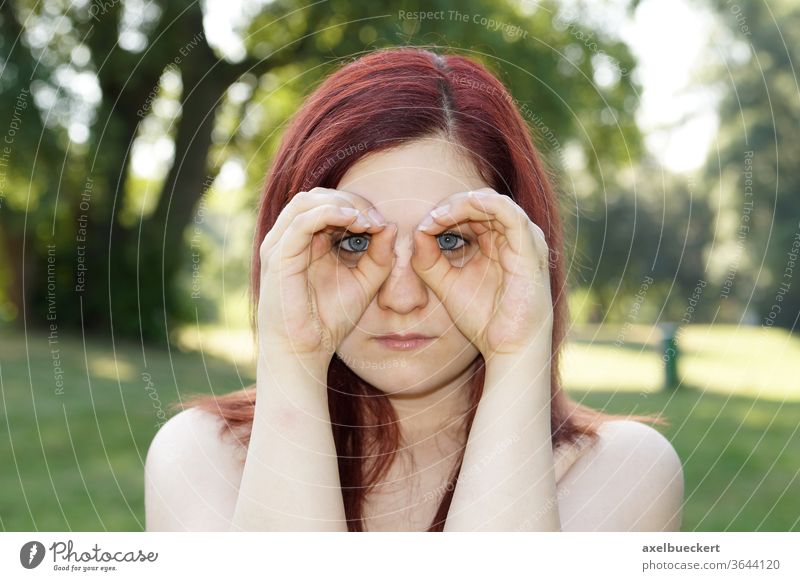 Hands imitating binoculars Observe Search Looking Surveillance see Binoculars Eyeglasses Spy hands Woman girl youthful Outdoors Nature portrait red hair Summer