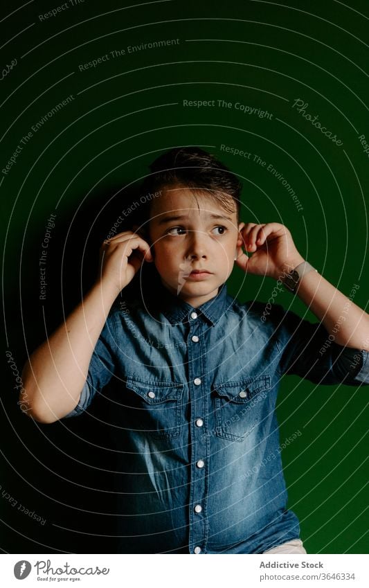 Schoolboy looking away posing in colorful wall using earbuds confident cool achieve unemotional friendly style lifestyle kid preteen portrait show optimist