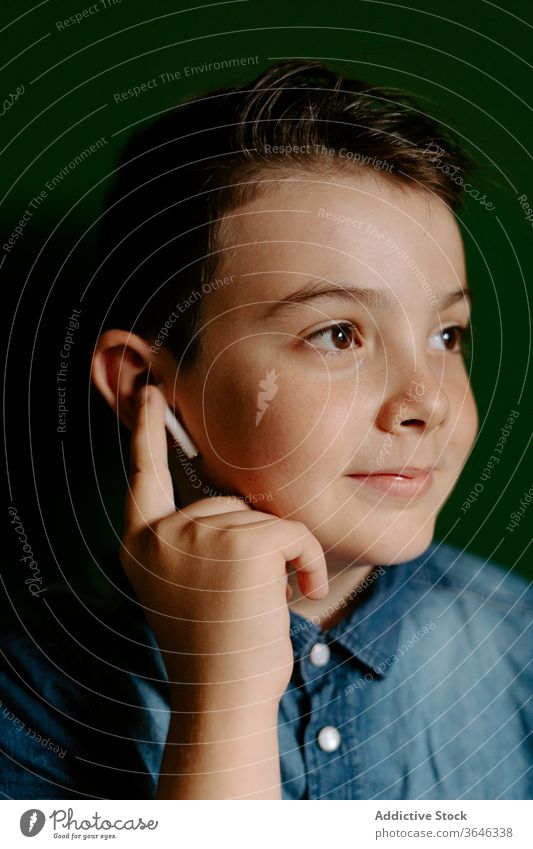 Schoolboy looking away posing in colorful wall using earbuds confident cool achieve friendly style lifestyle kid preteen portrait smile optimist content happy