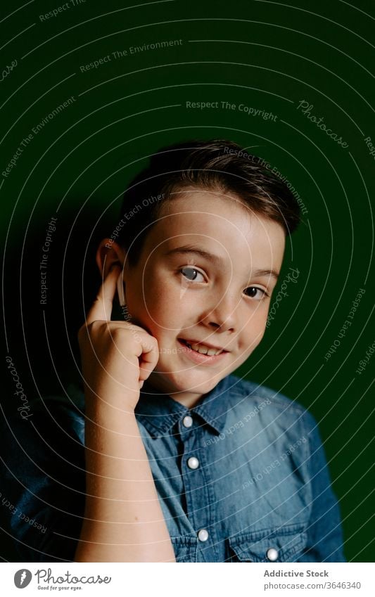 Schoolboy looking away posing in colorful wall using earbuds confident cool achieve friendly style lifestyle kid preteen portrait smile optimist content happy