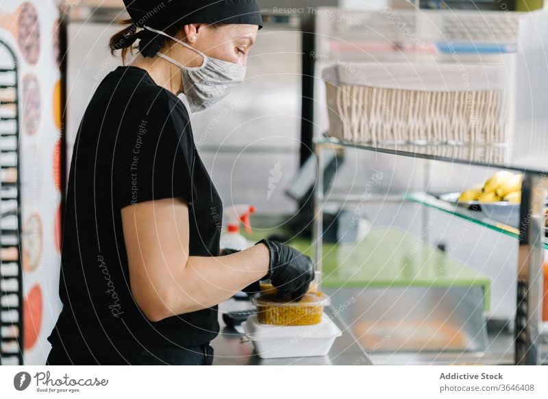 Cafe worker packing food in plastic container for takeaway waitress respirator coronavirus tasty busy glove concentrate woman cuisine service yummy delicious