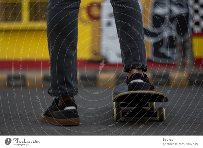 A young man standing while keeping his foot on a Skateboard. skateboarding summer new normal sports leisure lifestyle sneaker outdoors young adult skating