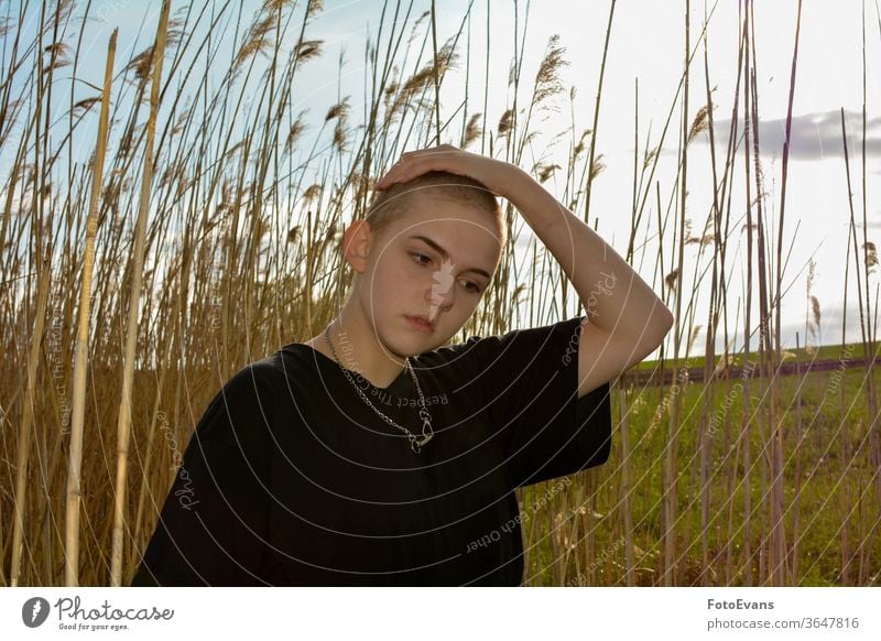 Girl  with very short hair  in nature, hand on the top of the head grass portrait sick fashion young cancer jewelry female attractive girl hair loss