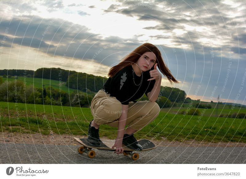 Young girl skates on a road in nature workout sporty enjoying fashion day beauty skating hand female attractive real fit hobby real person asphalt hair