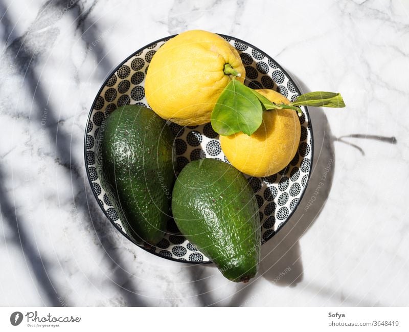 Avocado and lemons in a ceramic dish avocado marble flat lay fat food keto table natural hard light outdoors top view citrus vegetable fruit fresh summer