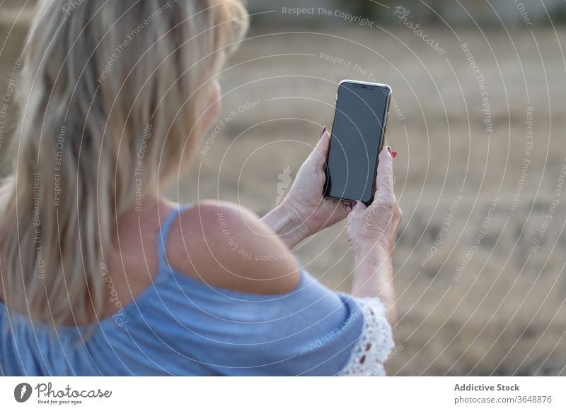 Content woman taking selfie during sunset in countryside field smartphone using scenic sundown rural photo dried device landscape gadget nature meadow