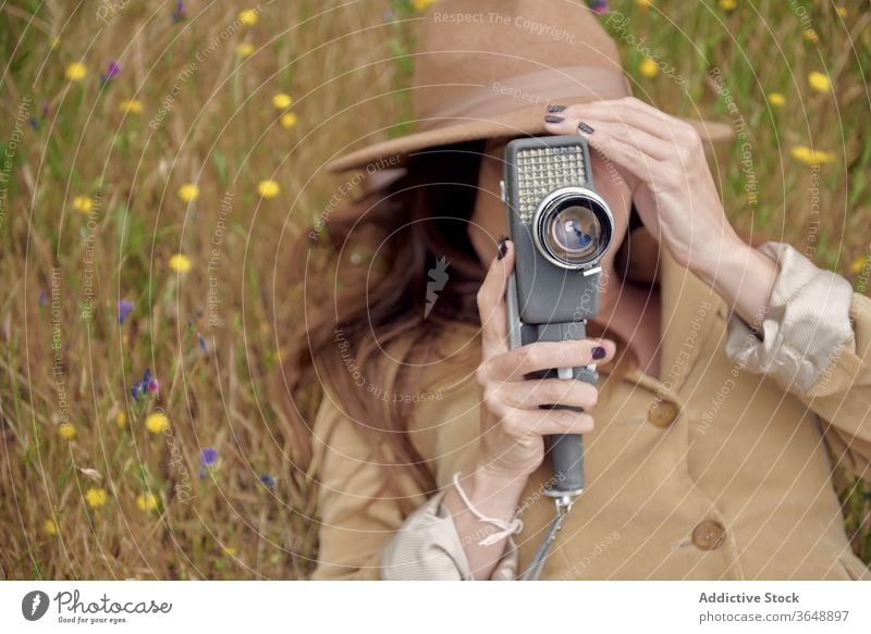 Cheerful photographer walking in park with vintage video camera retro bush bloom flower countryside summer shrub stroll garden nature idyllic calm positive