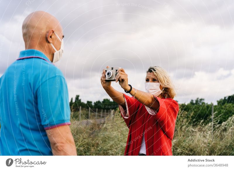 Woman taking photo of husband in nature couple take photo photo camera mask summer content covid 19 moment photography hobby together memory capture using