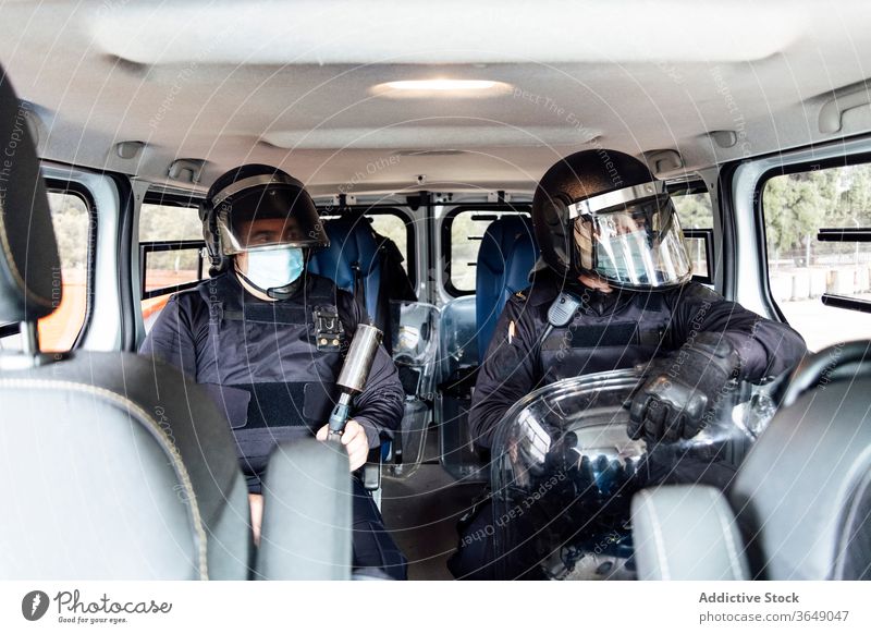 Police officer equipped with protective uniform in van with rifle man police operation street professional assault force service safety male helmet body armor