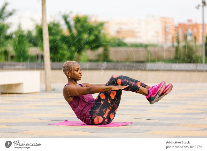 African American female sitting in Half Boat Pose on embankment woman half boat pose yoga practice balance sportswear health care city towel ardha navasana calm