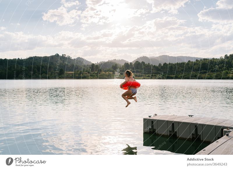 Girl jumping into lake with inflatable ring rubber girl pond bikini summer vacation having fun teenage moment water happy recreation relax holiday joy freedom