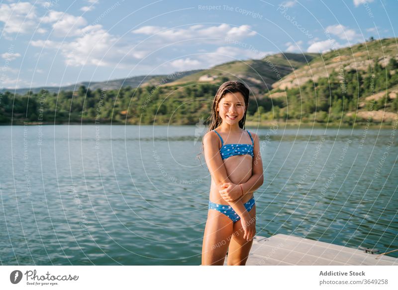 Playful girl standing in pier near lake pond summer holiday vacation enjoy child bikini water relax kid nature playful summertime sunny wooden daytime preteen