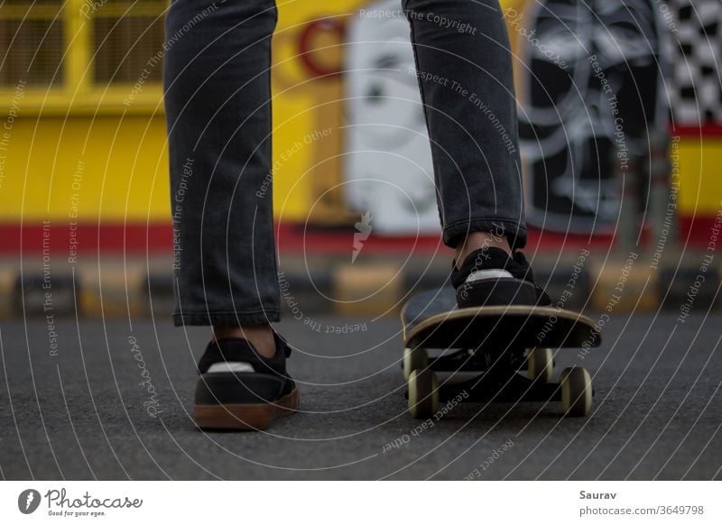 A young man standing while keeping his foot on a Skateboard. skateboarding summer new normal sports leisure lifestyle sneaker outdoors young adult skating