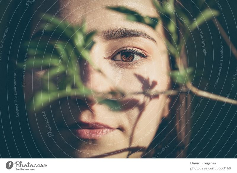 Young woman closeup face portrait in the woods beauty natural skin girl model leaf person pretty organic young nature branch tree attractive green female eyes