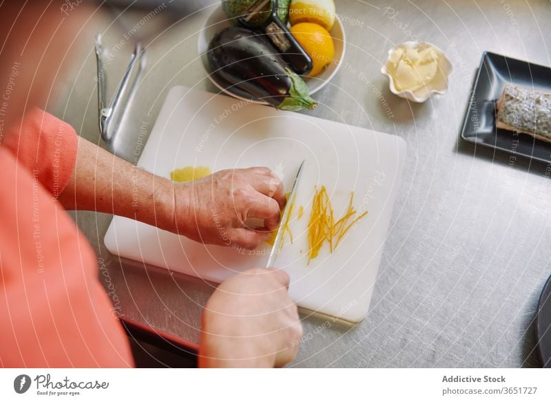 Crop unrecognizable cook peeling lemon while preparing garnish for fish zest chef prepare cut food culinary ingredient dinner menu recipe process lunch citrus