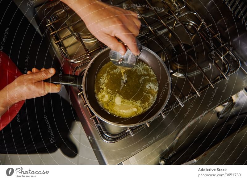 Crop unrecognizable cook pouring olive oil into frying pan chef melt butter stove culinary process prepare food recipe ingredient dinner lunch organic kitchen