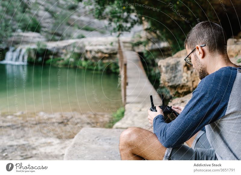 Focused man operating drone remotely control fly operate quadrocopter controller equipment unmanned flight male landscape mountain record video innovation