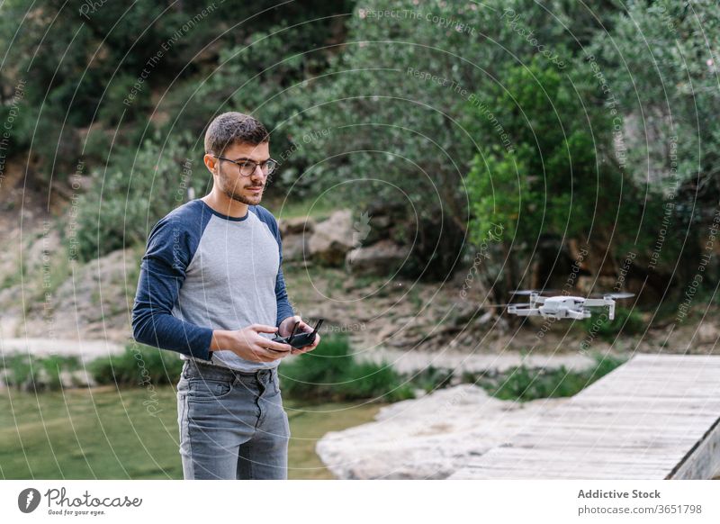 Focused man operating drone remotely control fly operate quadrocopter controller equipment unmanned flight male landscape mountain record video innovation