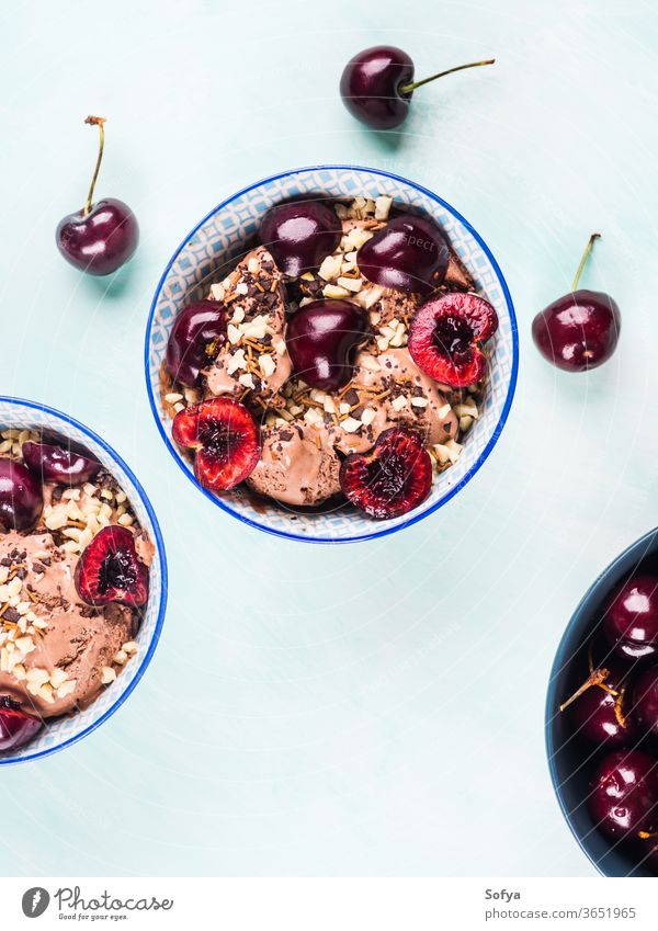 Chocolate ice cream sundae with cherries chocolate cherry scoop berries turquoise fruit sprinkles bright bowl topping sweet food garnish dessert summer