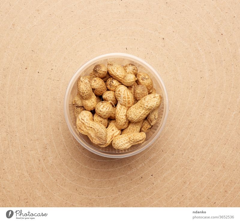 Inshell peanuts in a transparent plastic bowl nutrient nutrition nutshell open organic peel pile pod raw seed snack studio tasty vegan vegetarian whole brown