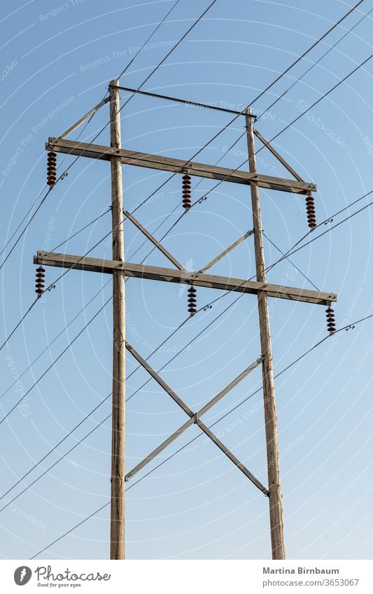 Wooden electic pole with a blue sky in the background rural voltage technology electricity power industry line light wire cable danger metal wooden industrial