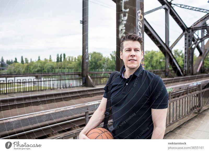 Man With a Basketball Posing Near Railway Tracks bridge caucasian Frankfurt Germany urban adult handsome model one person front facing lifestyle sports