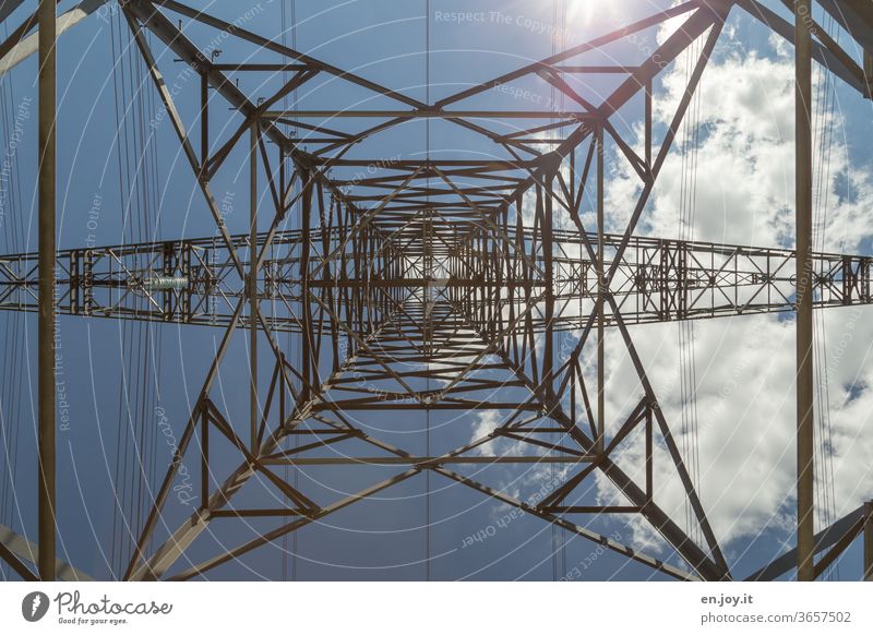 Power pole from below with blue sky, sunlight and a cloud in times of climate change Electricity pylon stream electricity Energy Energy industry