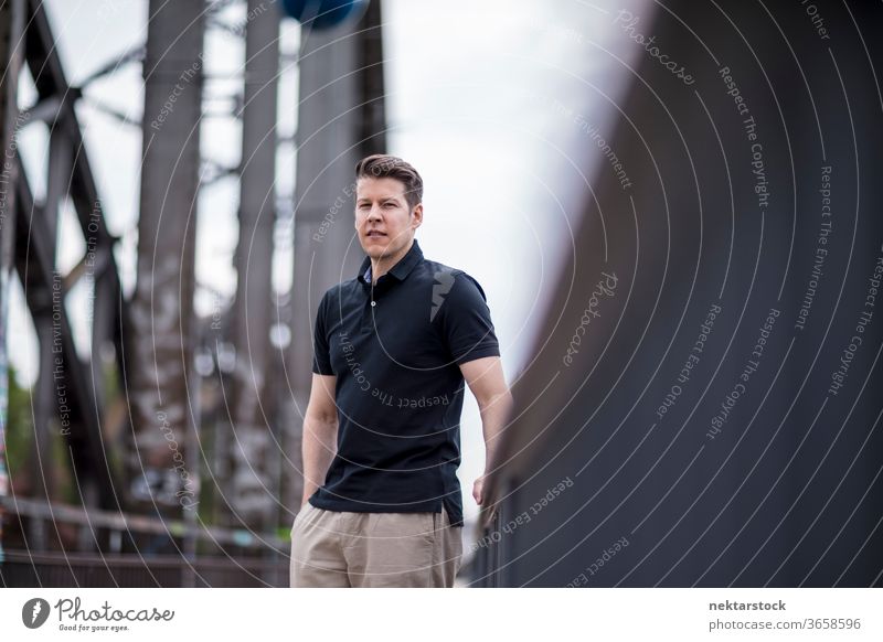 Portrait of a Handsome Man Posing on a City Bridge bridge adult caucasian city posing portrait standing balustrade selective focus one person urban handsome