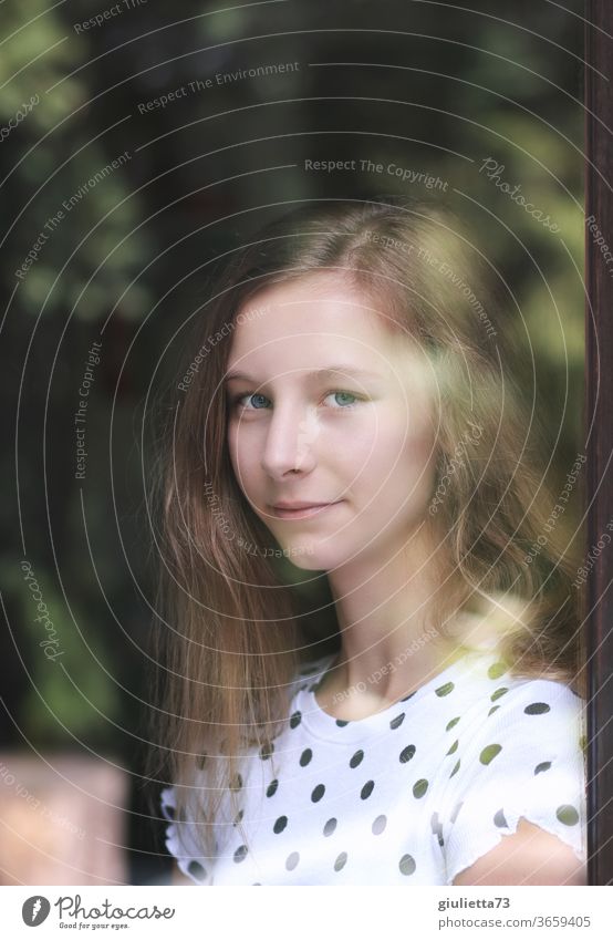 Portrait of a smiling girl through a window Half-profile portrait Central perspective Shallow depth of field blurriness Reflection Shadow Light Day