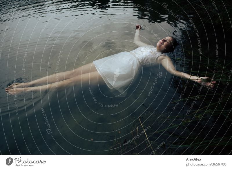 Close portrait of a young woman in a white dress lying in a lake Curly Purity Beautiful weather Trip Expectation Sunlight Joy Close-up Feminine Day Full-length