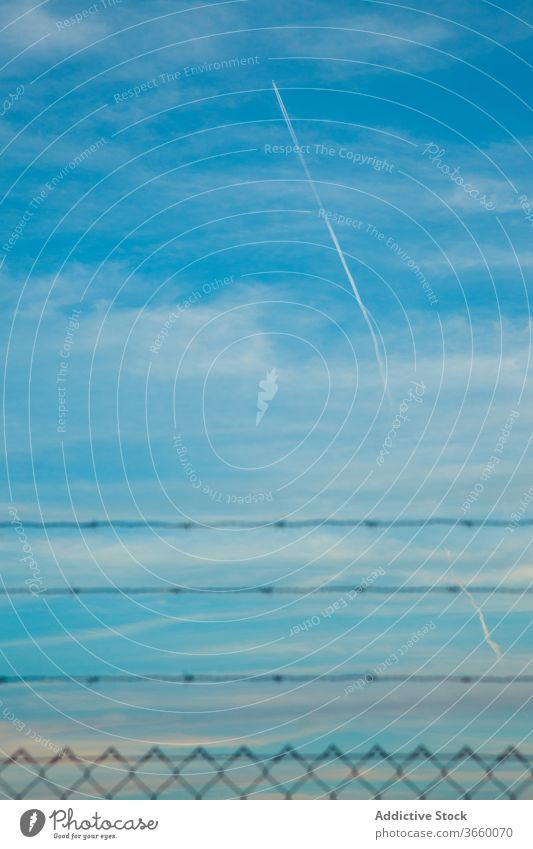 Airplane contrail on blue cloudy sky in daylight airplane blue sky vertical line security fence idyllic scenery spectacular calm skyline tranquil heaven