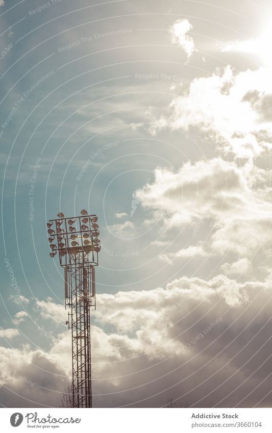 Spotlight tower under picturesque bright clouds spotlight sunshine sky stadium atmosphere illuminate glow spectacular scenery dramatic metal material calm