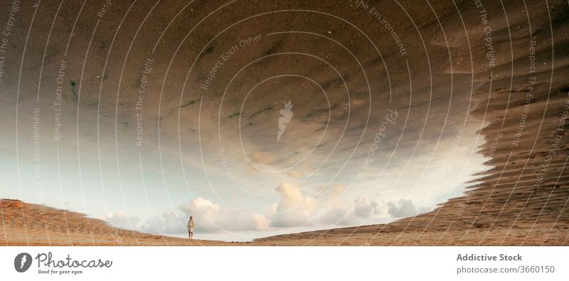 Faceless person on sandy dunes in desert reflection nature sky cloud mirage landscape journey adventure hot terrain trip calm arid valley cloudy dry beige