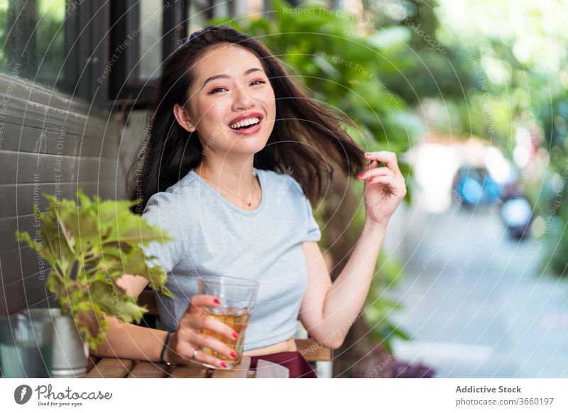 Relaxed ethnic woman in cafeteria drink weekend enjoy relax counter beverage refreshment female asian young sit cheerful glass lady charming smile delight glad