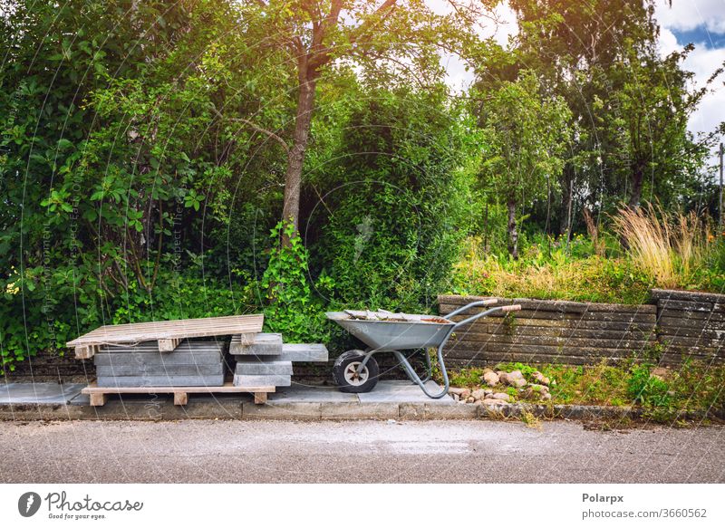 Wheelbarrow with tiles on a street project pavement stones tiling strong solid garden residential home laying block surface green backyard restoration heavy