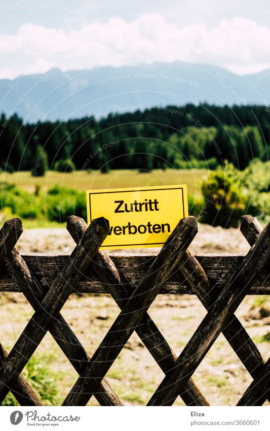 Landscape with woods and mountains and in front of it a fence and a sign saying "no entry". Unwanted tourism. Tourism unwanted No admittance Fence Pre-alpes