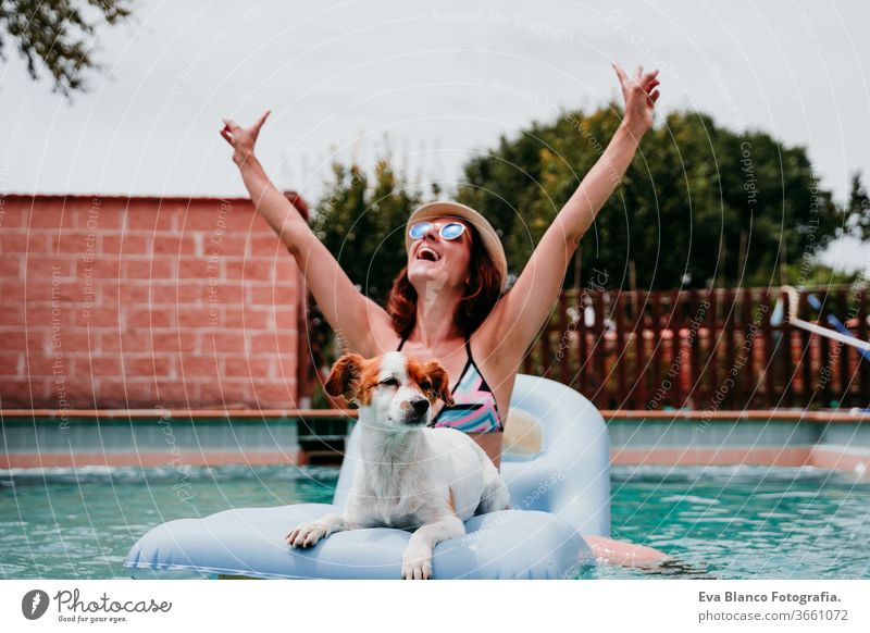 happy woman and dog in a pool having fun. dog sitting on inflatable and playing with owner. Summer time swimming pool blue water summer time love jack russell