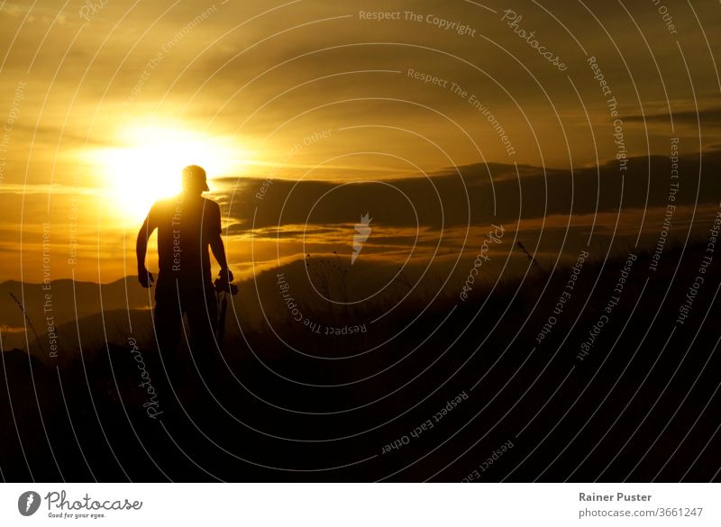 Dark silhouette of a young man wearing a hat in the last minutes before the sun sets. copy space dark darkness epic background hiking lifestyle model nature