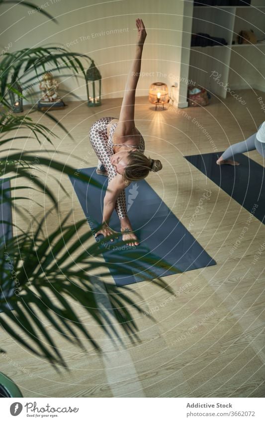 Concentrated woman performing Lunge with Arm Extended Up yoga asana in studio practice lunge with arm extended up flexible stretch wellness balance harmony