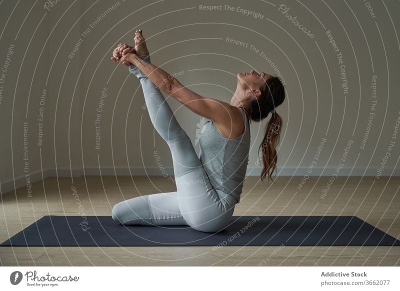 Focused woman performing Krauncasana stretching yoga pose practice studio heron flexible calm well being balance harmony wellness female fit sportswear healthy