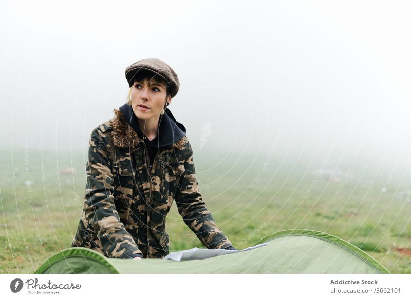 Woman with map standing near camping tent in foggy countryside woman navigate positive nature location route guide travel orientate contemplate valley traveler