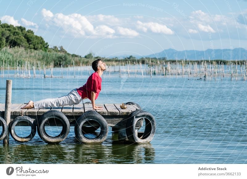 Calm male relaxing during yoga session on pier man meditate virasana hero namaste peaceful sea calm harmony healthy tranquil nature wellness gesture balance