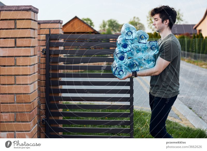 Young man throwing out empty used plastic water bottles into trash bin. Collecting plastic waste to recycling. Concept of plastic pollution and too many plastic waste. Environmental issue