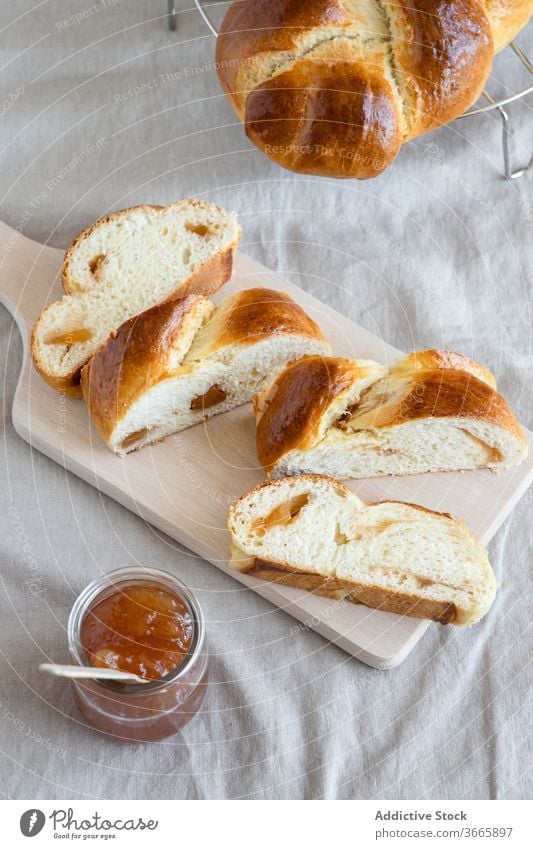 Brioche on wooden board near jam in jar brioche bun delicious homemade gastronomy slice pastry sweet glass jar baked goods cutting board cuisine yummy bakery