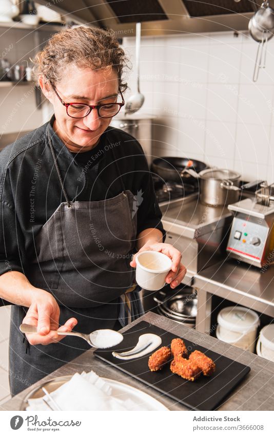 Chef dressing a plate of croquette handmade food kitchen chef cook snack cooking meal restaurant prepare appetizer work recipe preparation ingredient table