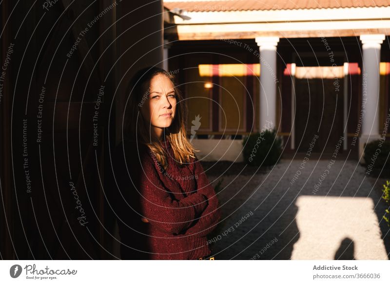 Calm woman against building with pillars calm pensive arms folded street urban casual thoughtful contemplate shadow ponder appearance exterior serious lifestyle