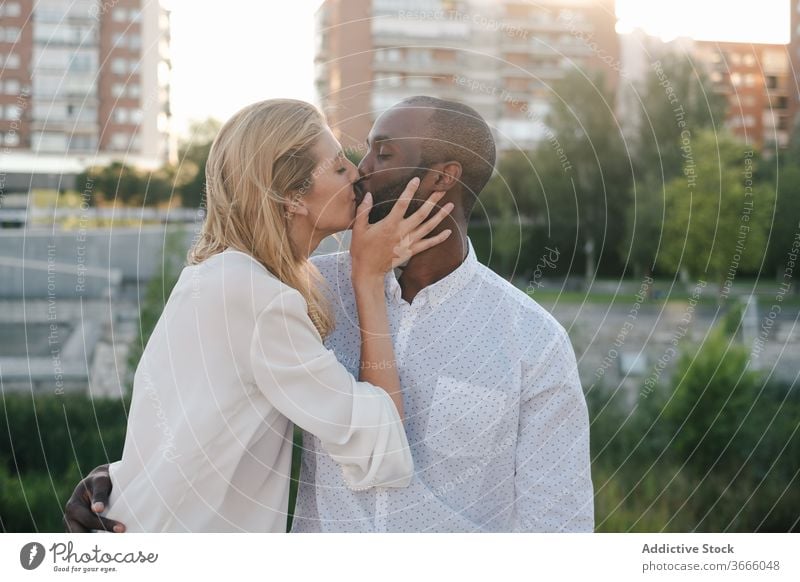 Happy diverse couple kissing on street bonding romantic positive relationship love happy affection embrace modern casual urban city lifestyle multiethnic