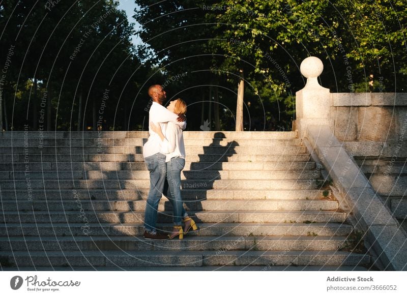 Cheerful loving multiethnic couple on street stairs walk urban hugging love cheerful relationship gentle carefree staircase evening madrid spain content